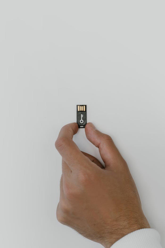 Hand holding a security-themed USB flash drive against a white backdrop, symbolizing digital security.